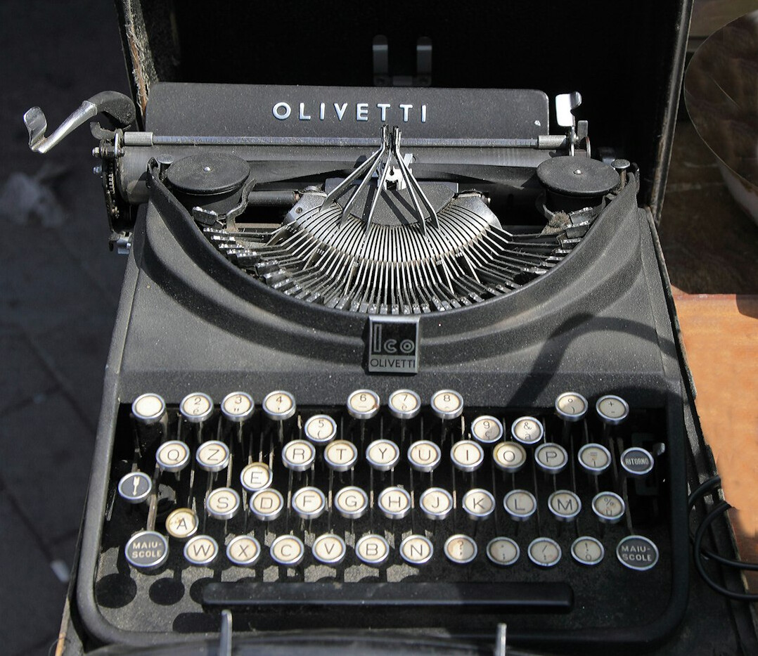 Close-up of hands typing on a laptop keyboard while writing a report